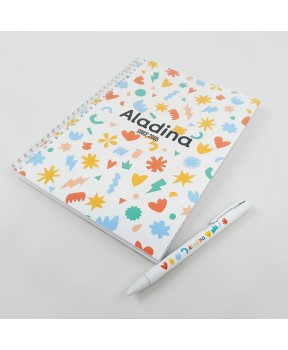 Bolígrafo solidario Aladina utilizado sobre libreta en entorno de oficina o estudio para escritura diaria